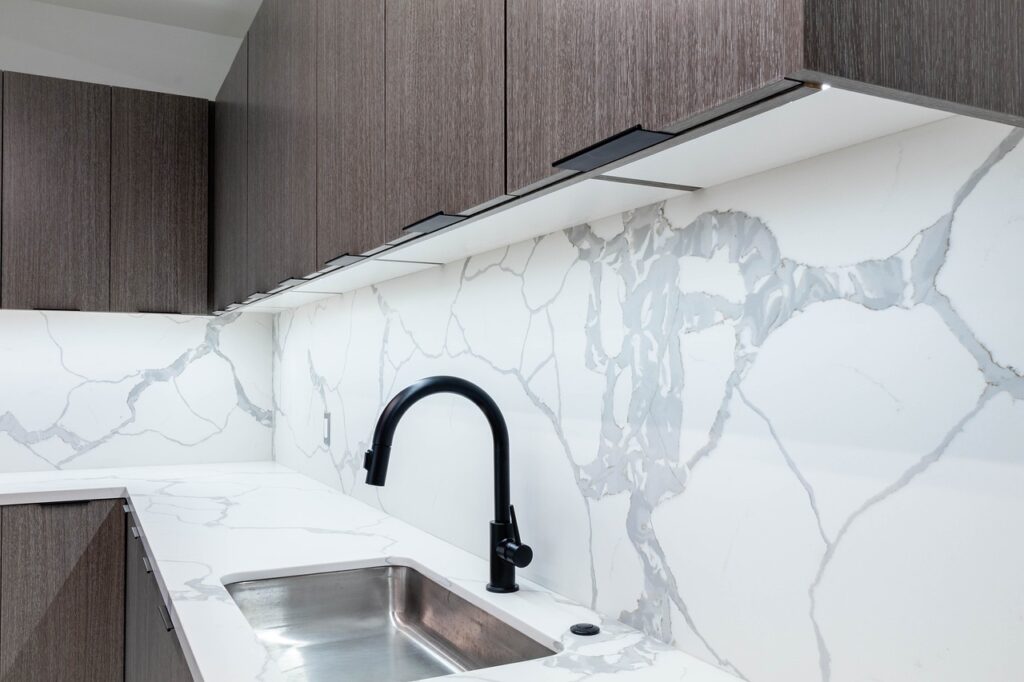 kitchen cabinets in wood grain vinyl wrap with white marble worktop and backsplash Al Barsha Dubai
